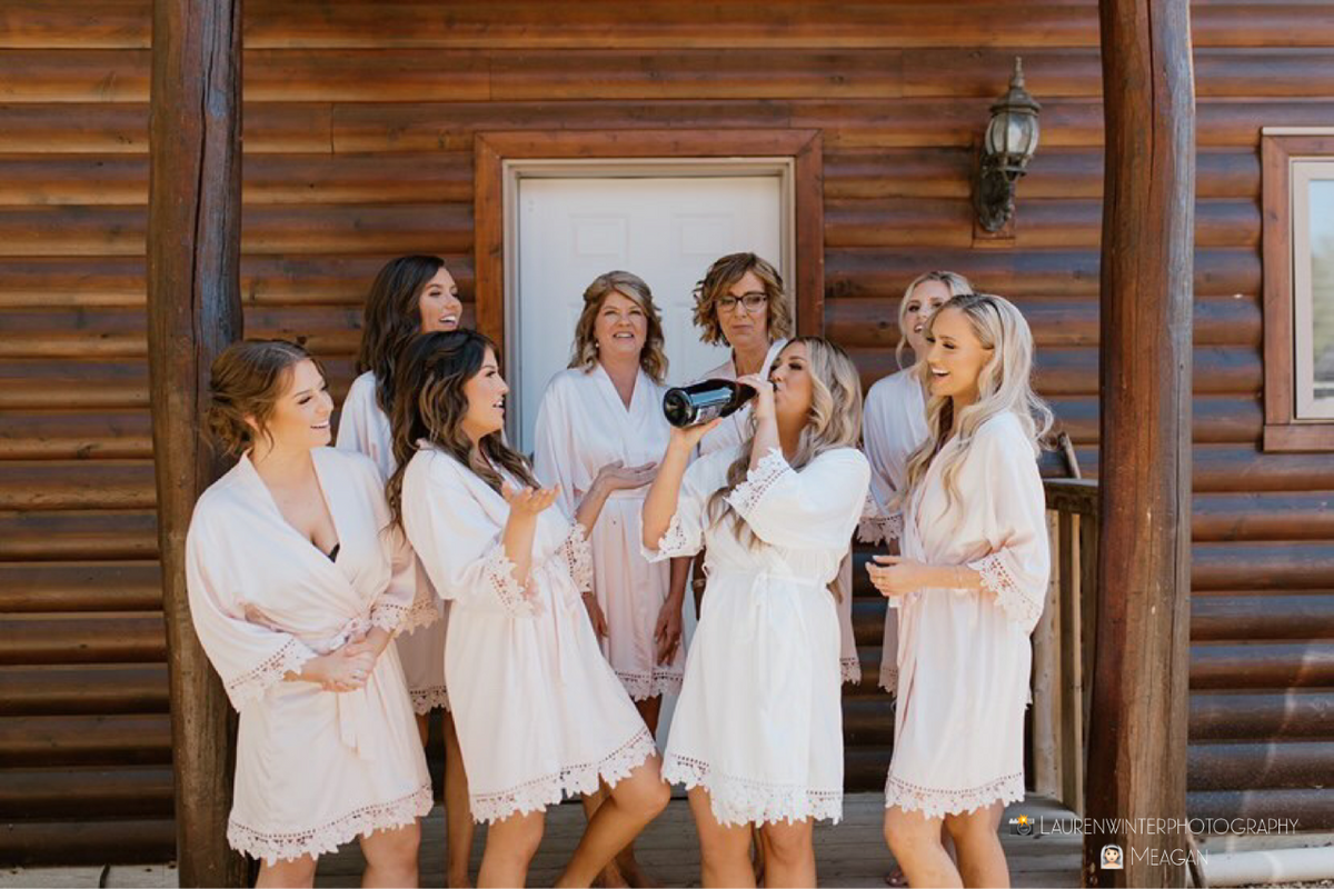 Bridal party wearing Aurora satin robes in white and blush satin. 431 the wedding company customer 