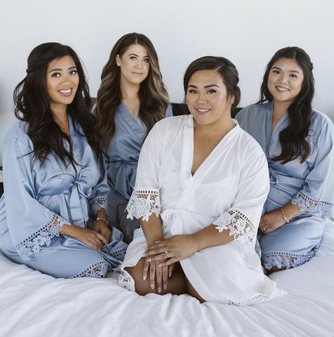 Customer wearing the Aurora white satin bridal robe. Bridal party wearing dusty blue satin robes