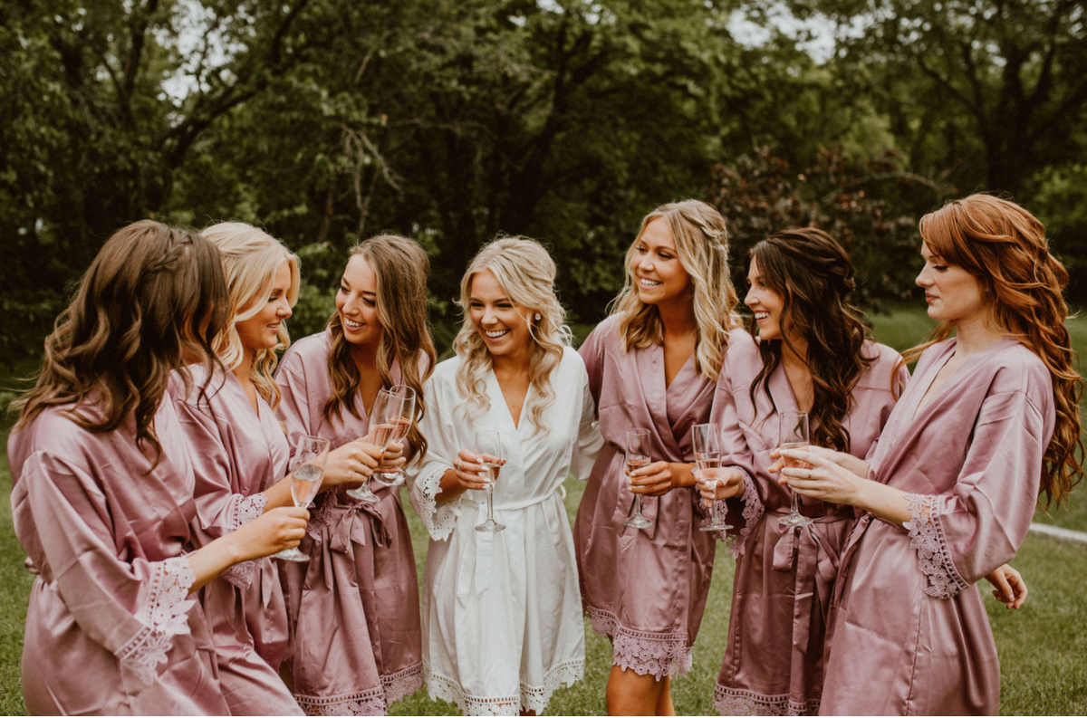 Customer wearing the Aurora white satin bridal robe. Bridal party wearing Mauve sating Aurora robes